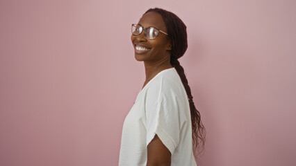 Wall Mural - Young african american woman smiling confidently over an isolated pink background capturing a vibrant and happy moment.