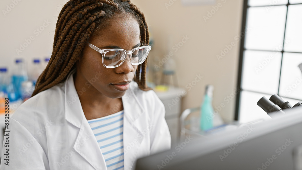 Concentrated african american woman with braids working in a science ...