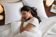 © Introvertia - Woman with long dark hair soundly asleep in bed with white sheets pillows and blankets