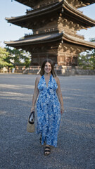 Canvas Print - Confident and carefree, a beautiful smiling hispanic woman casually walks towards the camera, posing infront of the majestic to-ji temple in kyoto, japan.