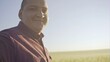 © procinemastock - Close up portrait of smiling man standing in green wheat field on sunset and looking at the camera - slow motion