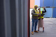 © eakarat - A group of men and women of professional container assemblers stand in a container shipping yard, looking at the preparation of containers. Logistics workers working at containers