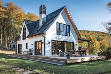 A modern farmhouse with a large gable roof, white walls and black windows.