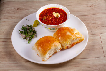 Wall Mural - Pav Bhaji is a fast food dish from India, Thick and spicy vegetable curry, fried and served with a soft bread Bun Pav and butter. selective focus