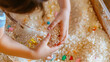 © AiiNa - Child exploring a sensory bin filled with rice and small toys, focusing on their hands and the sensory materials