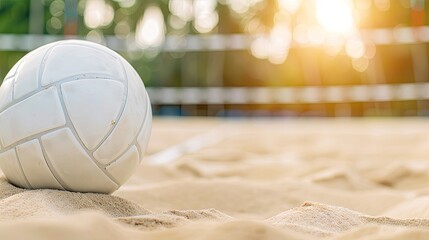 Wall Mural - A white volleyball sits in the sand on a beach, with a volleyball net in the background and the ocean in the distance