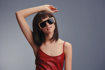 Wall Mural - Woman in red dress posing confidently for camera, wearing sunglasses, against urban backdrop