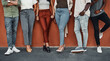 © MollerFinest/peopleimages.com - Wall, legs and business people with shoes, closeup and fashion with stylish outfit. Group, design team and high heels with sneakers, modern office and illustrator company with diversity or creativity
