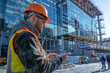 © EJManzaneque - A construction worker wearing a safety vest is using a tablet to check a building's blueprints
