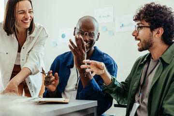 Co-workers in a collaborative office meeting sharing laughter and ideas together