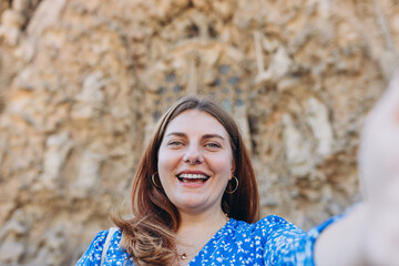 Wall Mural - Happy 30s woman tourist making selfie photo in front of the La Sagrada Familia Catalan Cathedral. High quality photo. Barcelona. Concept of travel, tourism and vacation in city.