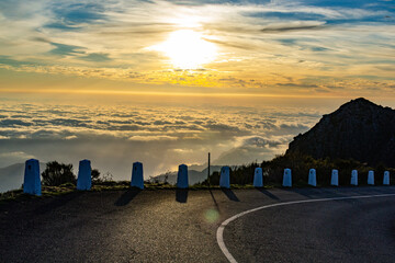 Sunrise high in mountains road over the clouds with backlit foreground in Madeira