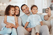 © SneakyPeakPoints/peopleimages.com - Parents, happy family and selfie of children on sofa for care, love or bonding together. Picture, mother and father with kids in home living room for social media photo, memory or relax with siblings