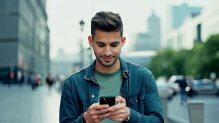 Wall Mural - Young man walking street texting on phone