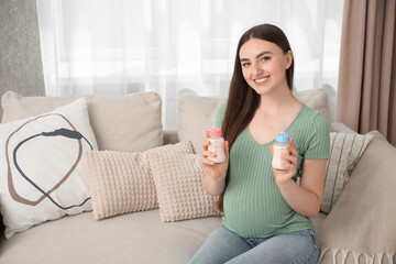 Canvas Print - Expecting twins. Pregnant woman holding two bottles of milk at home, space for text