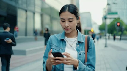 Wall Mural - Young woman walking street texting on phone