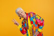 © MarGa - Elderly white woman making peace sign in colorful outfit against yellow background. Concept for fun attitude, joyful living, and vibrant senior