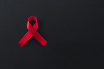 Poster - Red awareness ribbon on black background, top view. Space for text