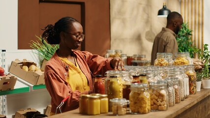 Vegan client examining types of pasta on sale at zero waste store, supporting local small business and low carbon footprint movement. Woman searching for natural eco friendly food supplies. Camera 1.