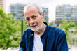 © Xavier Lorenzo - Happy senior man with grey hair and beard smiling at camera standing over urban background. Outside portrait of pensioner male.