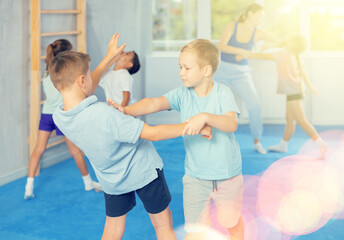 Wall Mural - Kids in sportswear exercising self-protection techniques in pair during class at gym