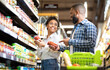 © Prostock-studio - Happy African Family Couple Buying Food In Supermarket, Choosing Products Walking With Cart Along Aisles And Full Shelves Purchasing Groceries Together. Black Spouses Purchasing Essentials Together