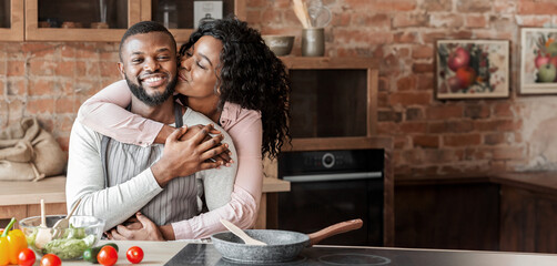 Wall Mural - Portrait of lovely african american couple embracing at kitchen, copy space