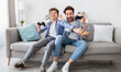 © Prostock-studio - Joyful dad and son with joysticks playing video games at home, boy distracting father with hand, faving fun together, sitting on sofa in living room. Fatherhood and leisure activities concept