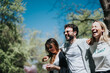 © qunica.com - Three diverse friends share a moment of joy and laughter at the park while enjoying cotton candy on a sunny spring day, promoting a sense of casual fun and togetherness.