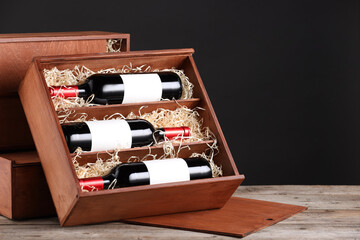 Poster - Box with wine bottles on wooden table against black background. Space for text