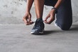 © A. Frank/peopleimages.com - Woman, shoes and tie lace outdoor for fitness, wellness and exercise as challenge, performance and goals. Athlete, start and ready by concrete wall with sneakers for training, cardio and body health