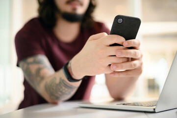 Poster - Businessman, hands and typing with phone by laptop for communication, news or research at office. Closeup of man, employee or user scrolling or texting on mobile smartphone for online chatting or app