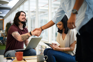 Poster - Business people, laptop and meeting with handshake in agreement, deal or b2b together at office lounge. Businessman shaking hands with employee or colleague for thank you or parthnership at workplace