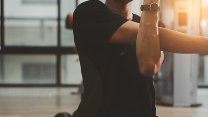 Man in black sportswear stretching arms with cross-body shoulder stretch pose and warming up before weight training in fitness gym. healthy sports lifestyle builds muscle, health and fitness concept.