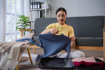 Woman packing her suitcase at home for an upcoming trip, choosing clothes and travel essentials with excitement and anticipation