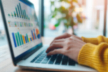 Poster - person typing on a laptop with financial graphs on screen, analyzing data. blurred background with g