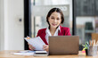 © David - Serious and focused financial accounting on documents paper work at office, Asian woman use calculator and laptop for calculating reports and summarizing accounts, business at work in casual clothes.