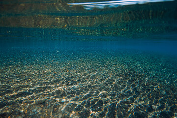 Wall Mural - Underwater crystal ocean with stone bottom and reflection on surface. Sea textures