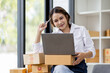 © David - Portrait business woman smile and use laptop checking information on parcel shipping box before send to customer. Entrepreneur small business working at home. SME business online marketing.