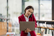 © David - Portrait of young asian financial woman sitting at desk and working on laptop while making call phone