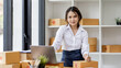 © David - SME concept. Young asian female ecommerce business owner prepares package box for customer and delivery check balance.  SME small business entrepreneur SME or freelance