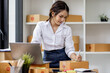 © David - SME concept. Young asian female ecommerce business owner prepares package box for customer and delivery check balance.  SME small business entrepreneur SME or freelance