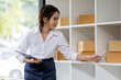 © David - SME concept. Young asian female ecommerce business owner prepares package box for customer and delivery check balance.  SME small business entrepreneur SME or freelance