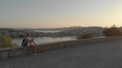 Wall Mural - Enjoying vacation in Greece. Young traveling woman enjoying sunset on the view point. Ermioni bay and yacht marina.