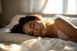 © Minerva Studio - Beautiful young woman sleeping peacefully in bed with sunlight streaming through window