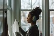 © Regina - Young African American woman wiping down cleaning windows during spring cleaning, face focused determined.