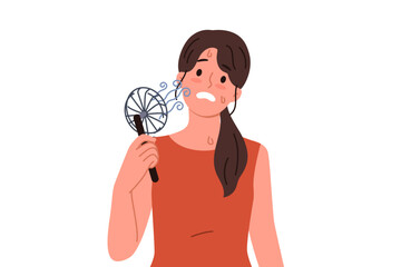 Woman uses electric fan to stop sweating and prevent exhaustion in hot summer weather. Small electric fan inside girl suffering from warming temperatures and lack of air conditioning