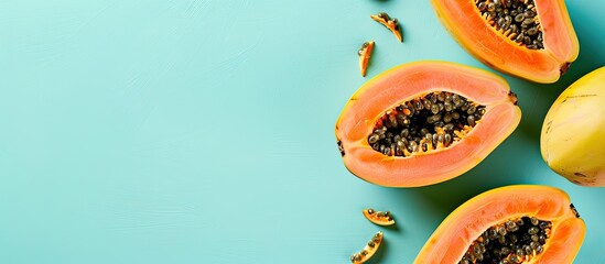 Poster - Ripe papaya fruits on a light turquoise backdrop with a flat lay presentation and a copy space image available