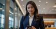 © muqadas - Businesswoman using a mobile phone in an office lobby