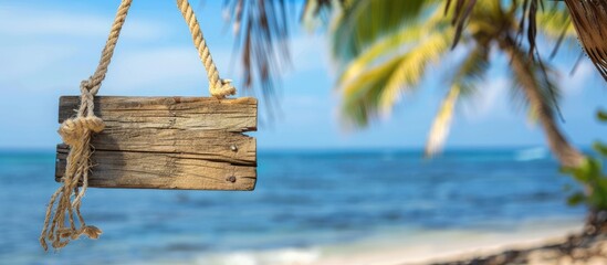 Poster - A beach themed sign crafted from manila rope placed on a weathered wooden board with a coconut pole set against a blurred beach and a clear blue sky background ideal for summer themed designs with co
